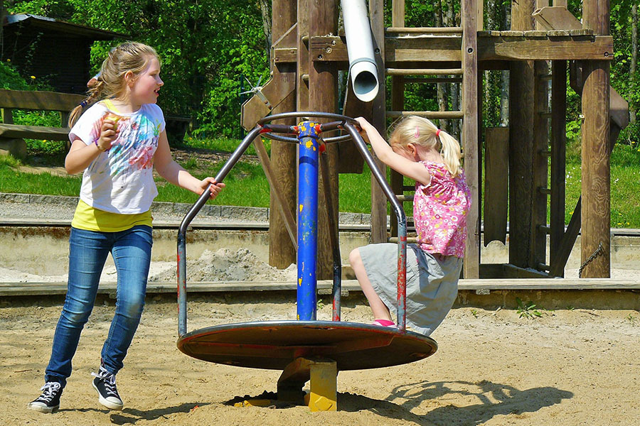 Zwei Kinder, die bei schönem Wetter auf einem Spielplatz spielen