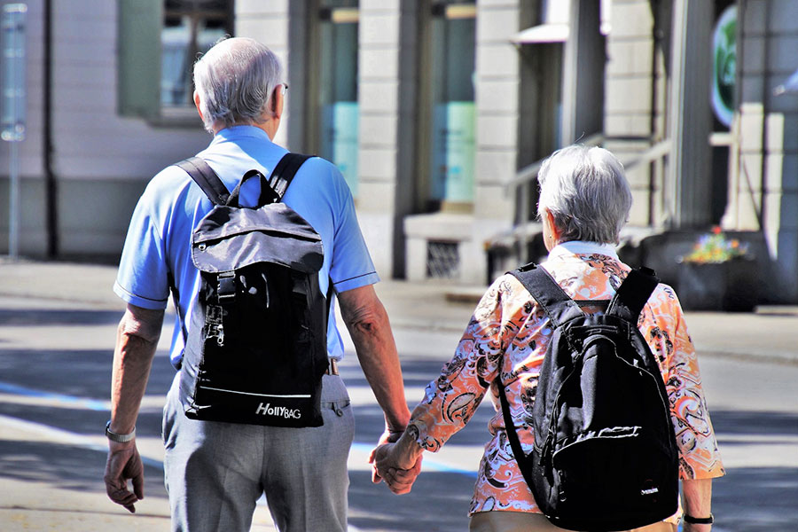 Zwei älterer Mann und eine ältere Frau, die Hand in Hand spazieren gehen
